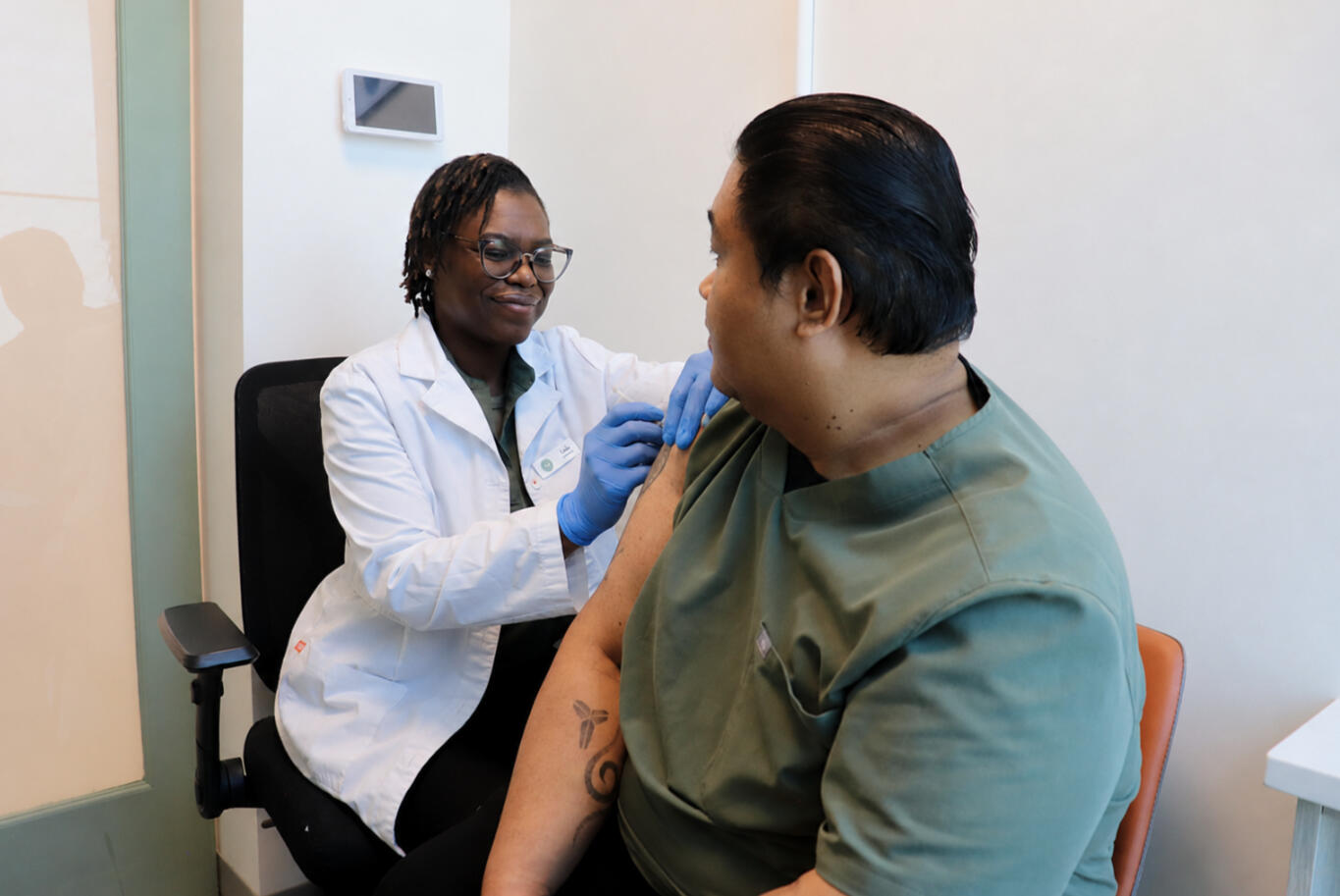 A smiling woman with teen who has a vaccine bandage on her shoulder sitting on her lap