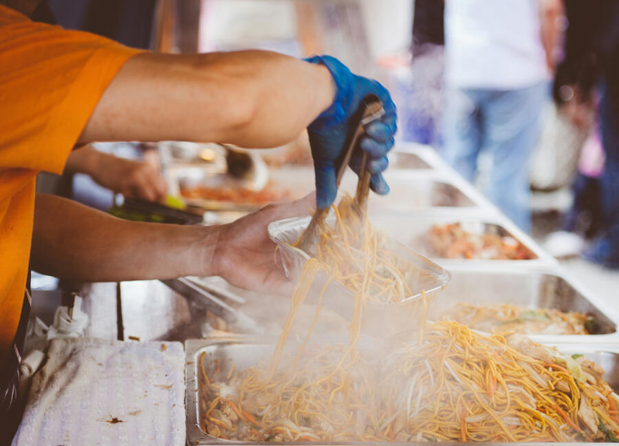 Hot steaming street food being put into a small container
